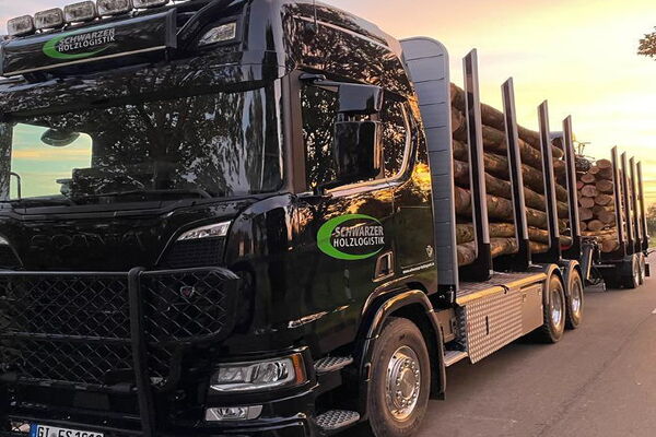 Stammholz / Brennholz Transport - Schwarzer Holzlogistik Bild eines Stammholztransport-LKWs auf der Landstraße